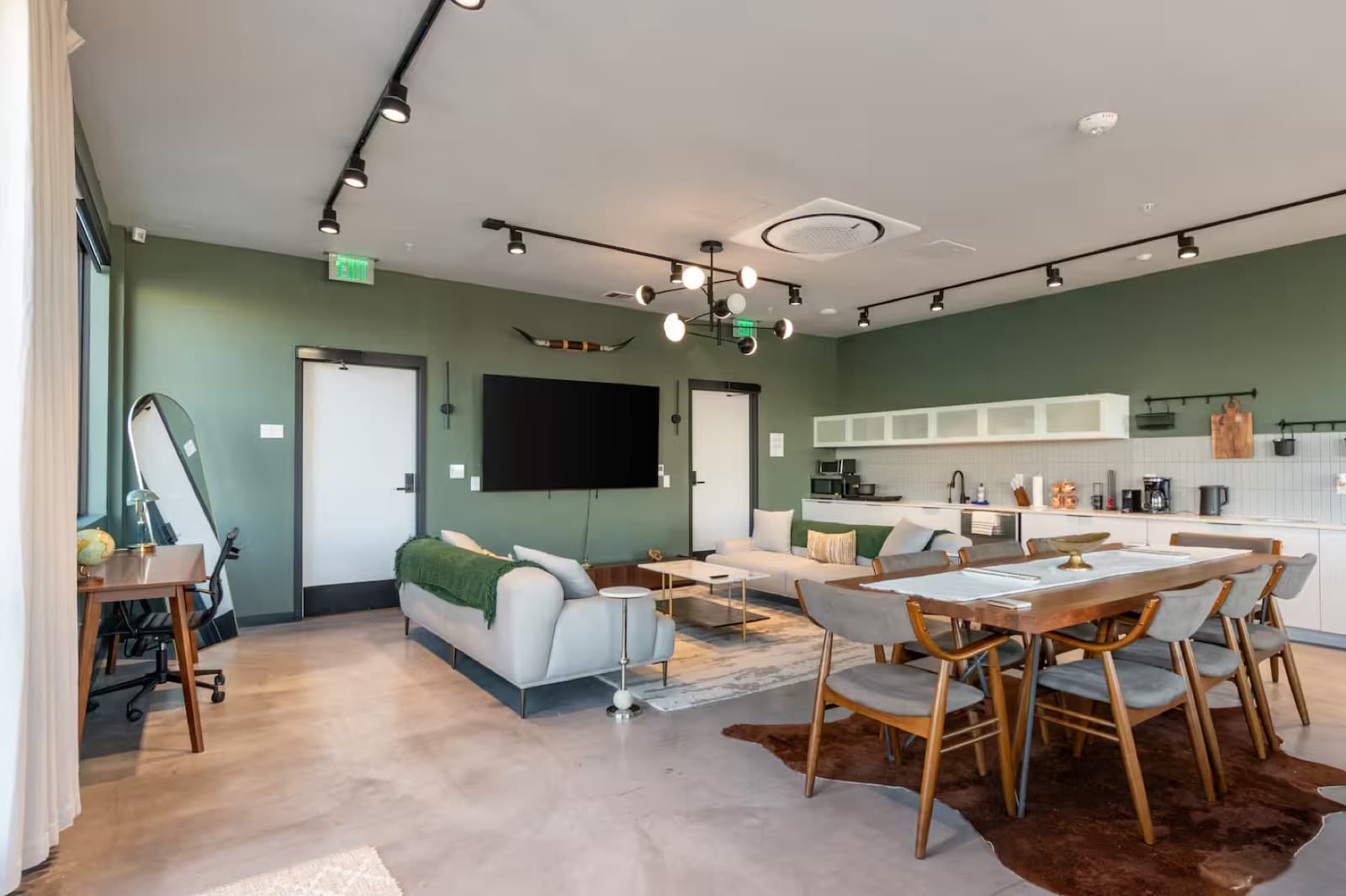 Capitol Living penthouse living area with dining table, TV wall, and open kitchen