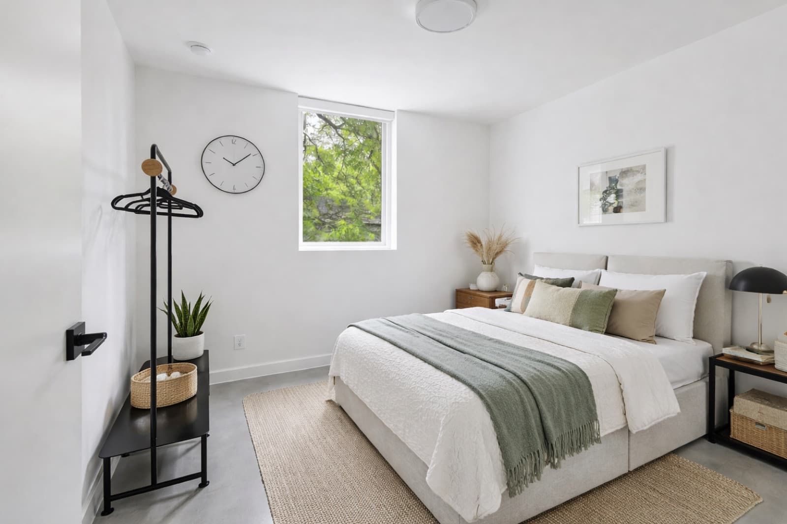 Furnished bedroom with clothing rack, jute rug, and green throw at Capitol Living