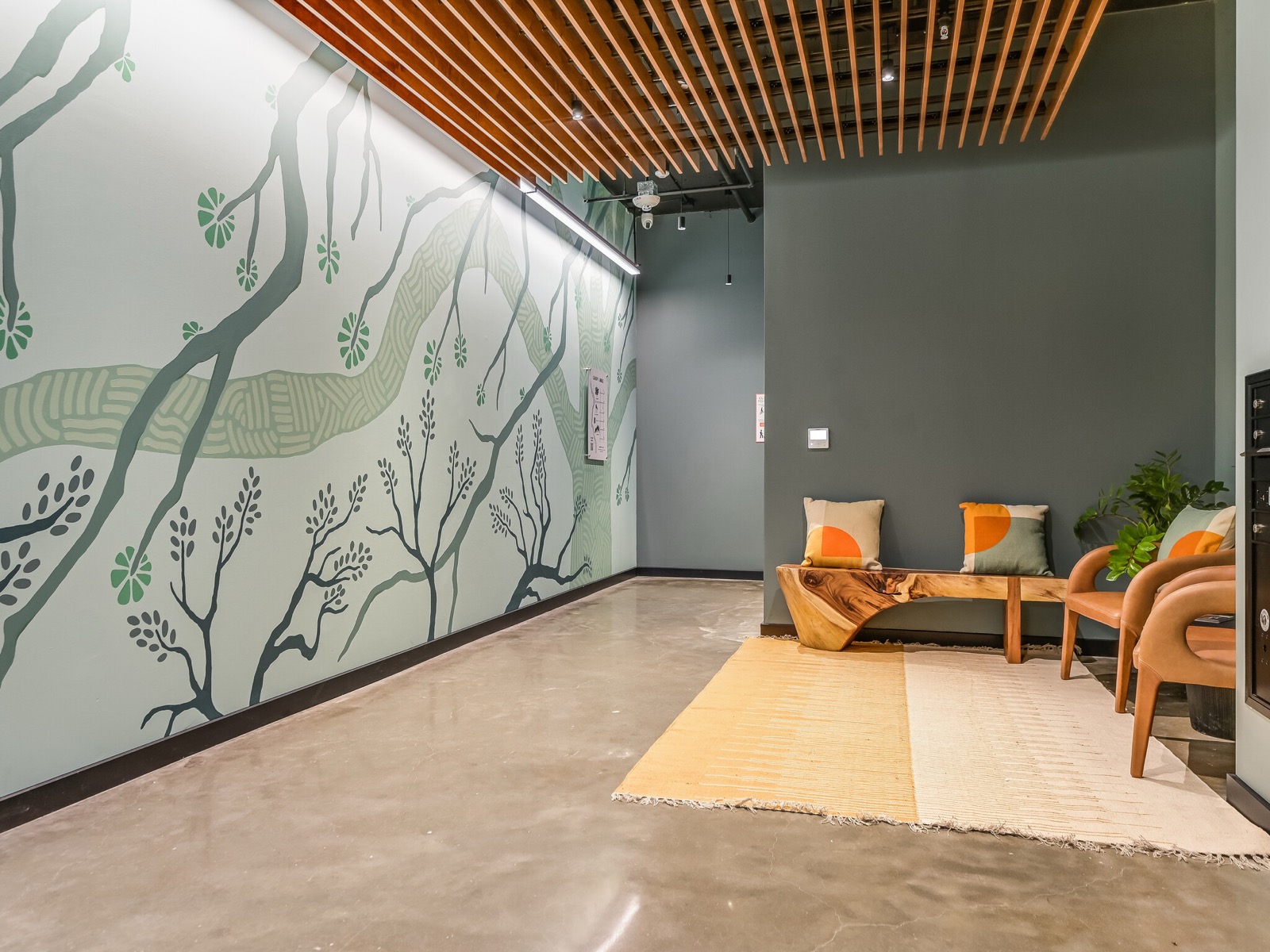 Capitol Living designer lobby with botanical mural and wood-slat ceiling